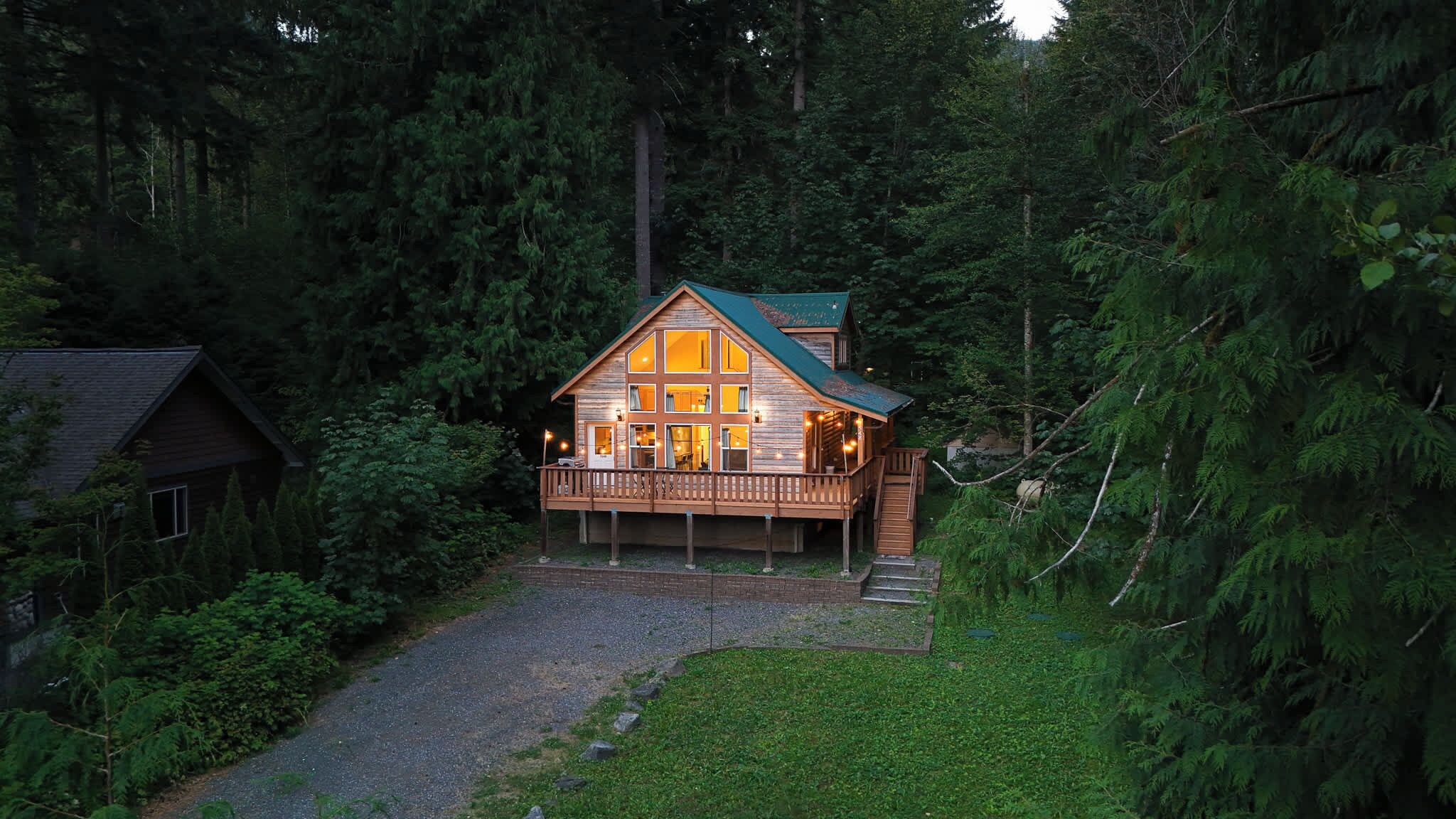 Een chalet met een veranda, omgeven door dicht bos.