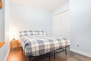 A bedroom with a bed, bedside table, lamp, and a wardrobe. - Updated Glacier Springs Basecamp w Grill (Deming)