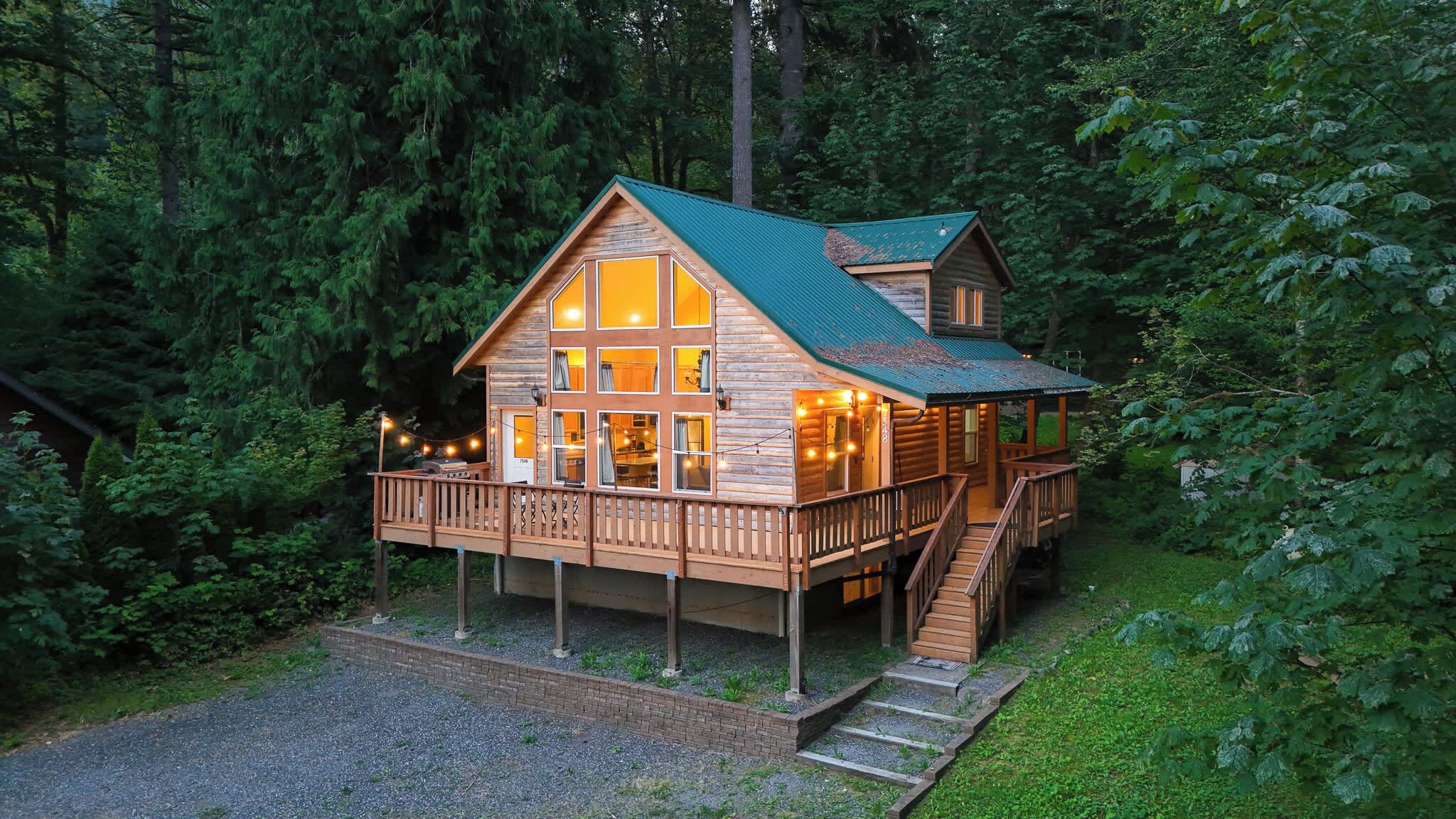 A wooden cabin with a balcony, surrounded by dense forest.