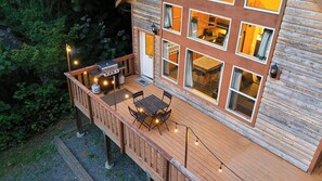 A wooden deck with a barbecue, outdoor seating, and large windows. - Updated Glacier Springs Basecamp w Grill (Deming)