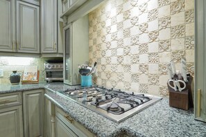 A kitchen with a gas stove, two ovens, and a decorative backsplash. - East Beach Estate Between Ocean & Estuary | Salt Pool + Spa | Shuffleboard Table (St. Simons Island)