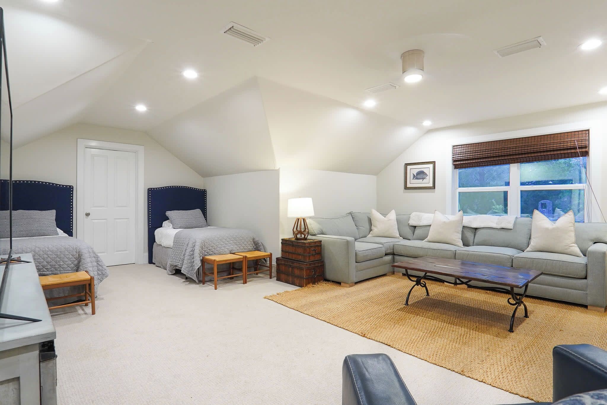 A bedroom with a bed, bedside table, lamp, and a window with blinds.