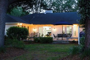 A house with a covered patio, outdoor furniture, and string lights. - Parkside Retreat | Walk to St. Simons Village, Pier & Park | Pet Friendly (St. Simons Island)