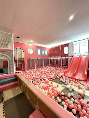 Ein Kinderspielbereich mit Ballbecken, Rutschen und Klettergerüsten.