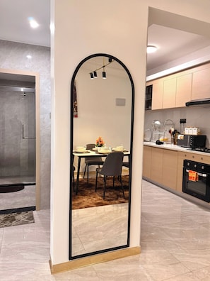 Een moderne keuken met een eethoek, een douche en een spiegel die de ruimte weerspiegelt.