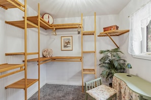 A room with a bunk bed, a small table, a chair, a plant, and a window with lace curtains. - Charming Estes Lake Haus with Stunning Mountain Views & Walk to Lake Estes (Estes Park)