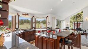 Una cocina moderna con una isla grande, armarios de madera y vista a un paisaje verde.