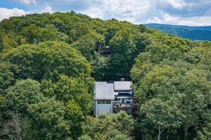 A house surrounded by dense forest, with a clear sky above. - Yuppie Buck |  2mi to Ski Resort, Stunning Views & Game Room (Beech Mountain)