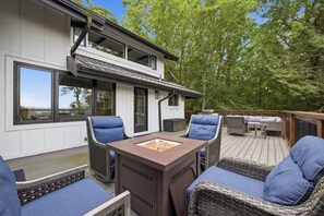Eine Terrasse mit Gartenmöbeln, darunter Stühle und ein Tisch, sowie einem Feuerkorb.