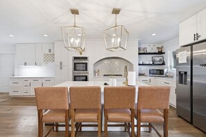 Une cuisine moderne avec des meubles blancs, un îlot central et un réfrigérateur en acier inoxydable.