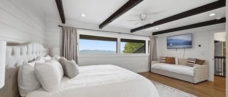 Un dormitorio con cama, sofá, televisión y ventana con vistas.