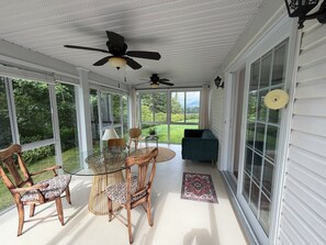 A covered porch with a table and chairs, a ceiling fan, and a view of the outdoors. - Lovely 3-bedroom house with AC in Saint-Gabriel-de-Valcartier (Saint-Gabriel-de-Valcartier)