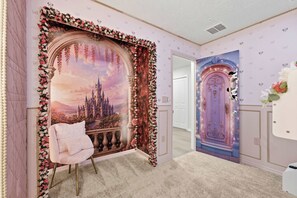 Ein Zimmer mit großem floralem Wandbild, einem komfortablen Sessel und einer Tür mit dekorativen Verzierungen.