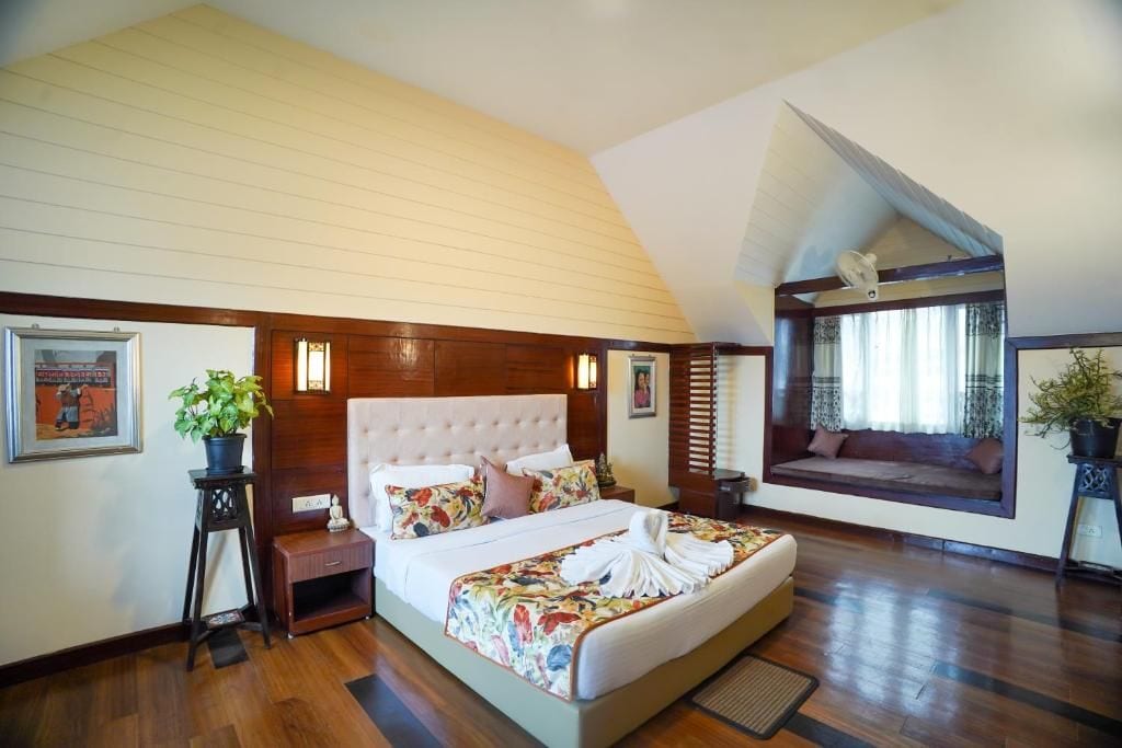 Un dormitorio con una cama grande, un rincón con asiento junto a la ventana y una planta en maceta.