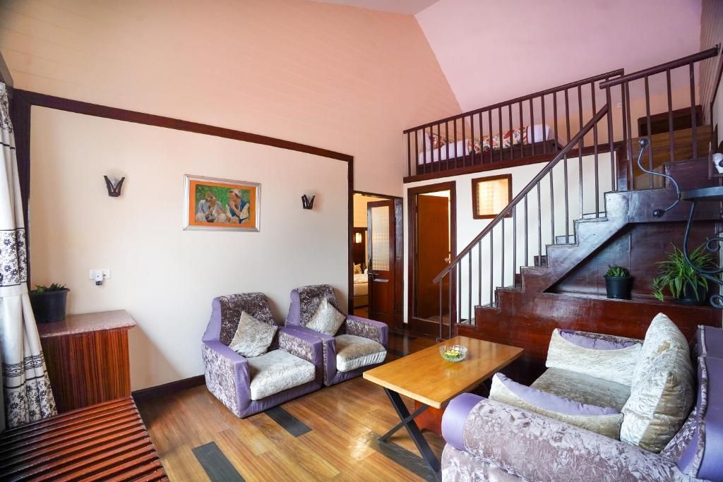 A living room with a wooden staircase, two sofas, a coffee table, and a painting on the wall.