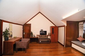 A room with a sloped ceiling, wooden flooring, a television, a sofa, a table with chairs, and a potted plant. - Gigi Aurea Resorts & Spa (Gangtok)
