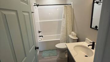 Une salle de bain comprenant des toilettes, un lavabo, une douche et une porte.