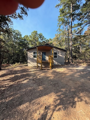 A small cabin with a wooden porch and a dirt ground.