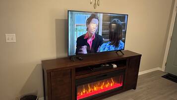 A television on a wooden entertainment center with a fireplace below.