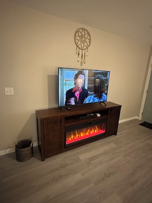 A television on a wooden entertainment center with a fireplace below.