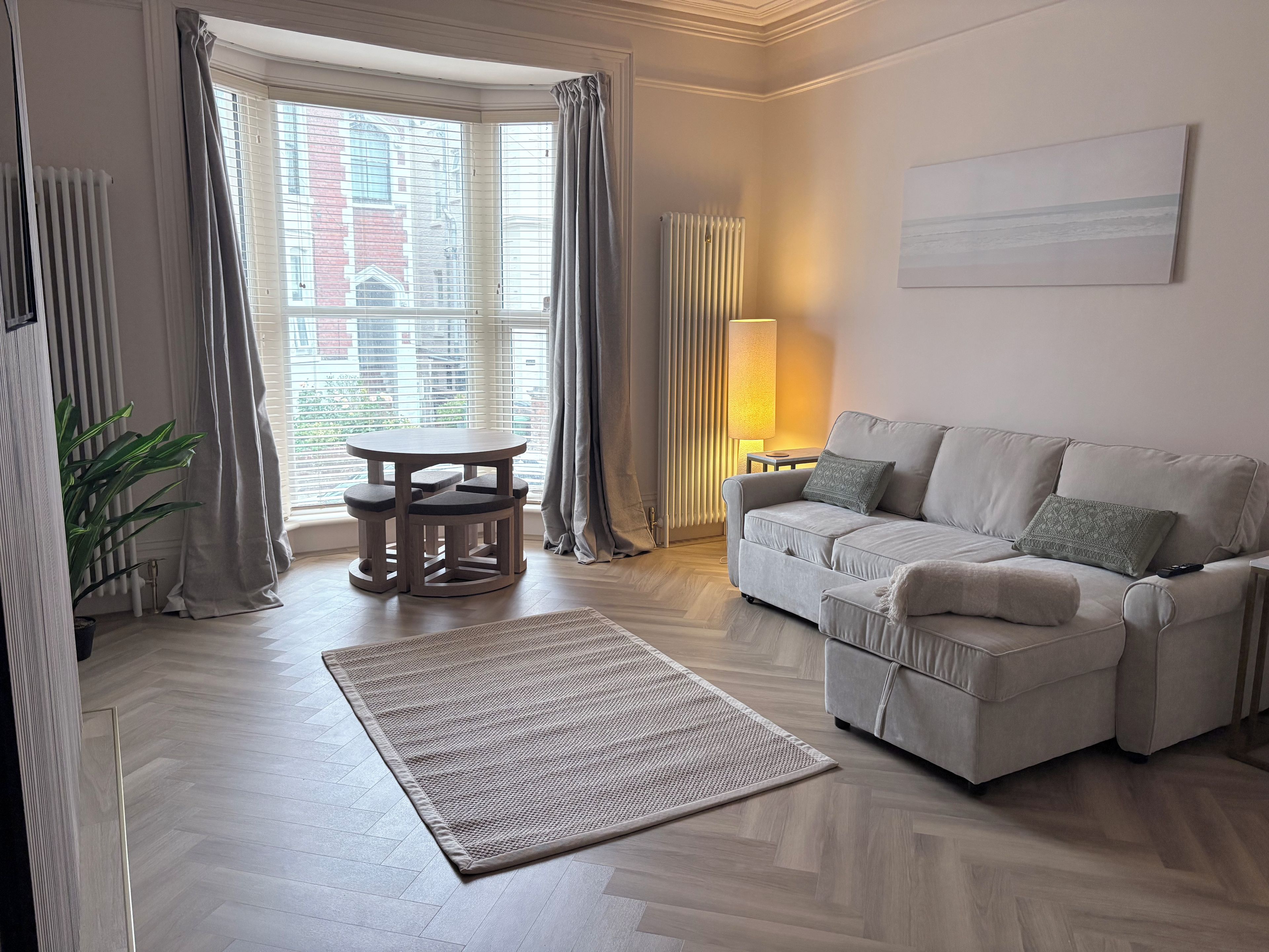 A modern living room with a sofa, a round table, and a lamp.
