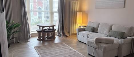 A modern living room with a sofa, a round table, and a lamp.