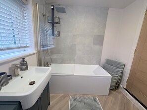 A modern bathroom with a bathtub, a shower, and a toilet.