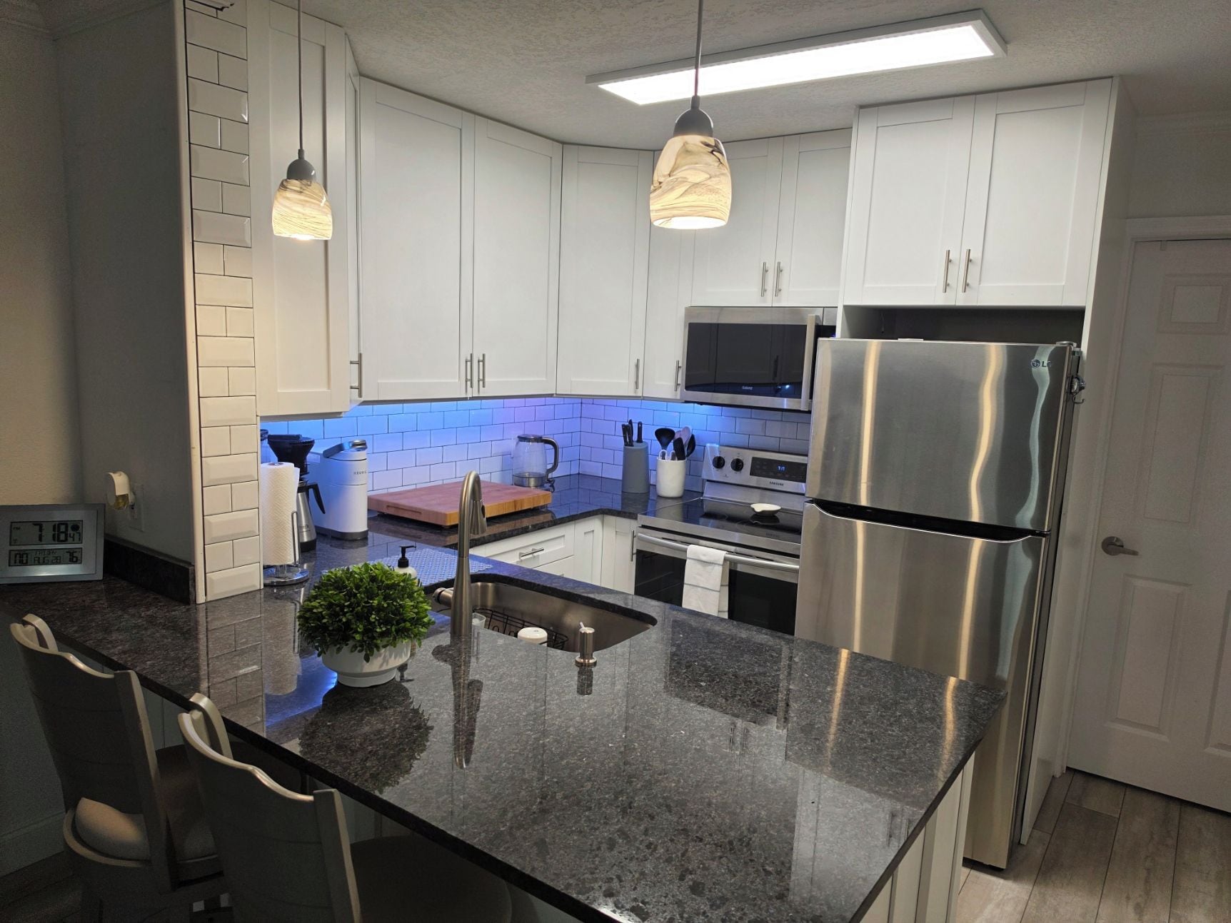 A modern kitchen with white cabinets, stainless steel appliances, and a granite countertop.