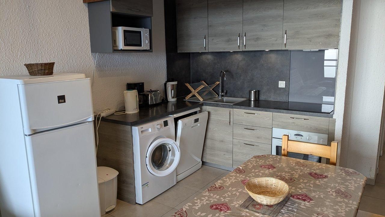 A compact kitchen with a washing machine, a microwave, and a dining area with a table and chairs.
