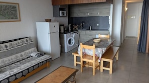 Ett kompakt bostadsutrymme med en soffa, ett matbord med bänkar, en tvättmaskin och en mikrovågsugn.