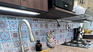 A kitchen with a stainless steel sink, dark wooden cabinets, a microwave, and a tiled backsplash. - Contemporary Oasis, Serene Modern Retreat 2BR house with AC in vibrant Santa Ana (Santa Ana)