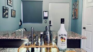 Un comptoir de cuisine avec une bouteille de rhum Malibu Original, un shaker à cocktails et divers ustensiles de bar.