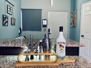 En köksbänk med en flaska Malibu Original-rom, en cocktailshaker och olika bartillbehör.