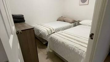Habitació petita i neta amb dos llits, un armari de fusta i un quadre penjat a la paret.