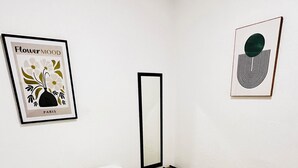 A bedroom with a bed, a bedside table, a mirror, and two wall art pieces. - Contemporary Oasis, Serene Modern Retreat 2BR house with AC in vibrant Santa Ana (Santa Ana)