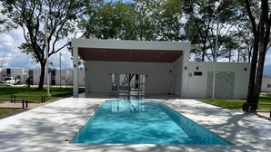Ein rechteckiger Pool mit glasklar blauem Wasser, umgeben von einer gefliesten Liegefläche.