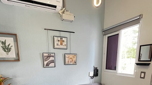 A living room with a grey sofa, a woven rug, and wall-mounted air conditioning unit. - Contemporary Oasis, Serene Modern Retreat 2BR house with AC in vibrant Santa Ana (Santa Ana)