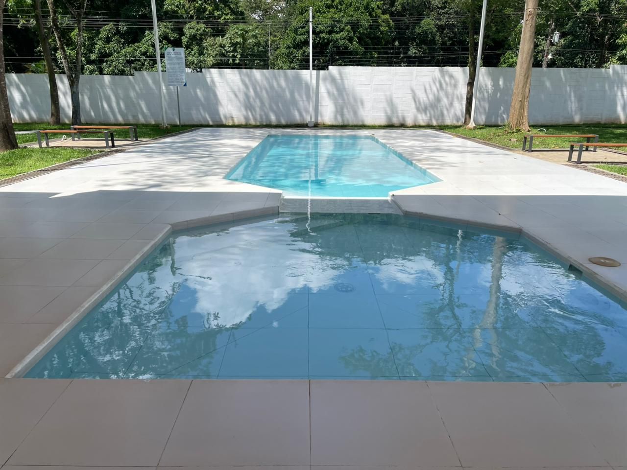 Ein rechteckiger Pool mit glasklarer, blauer Wasseroberfläche, umgeben von einer gefliesten Liegefläche.