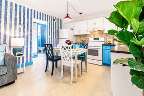 A modern kitchen with white cabinets, a red pendant light, and a blue countertop. - Coastal Haven | Pet-Friendly | Near the Beach | Treasure Island (Treasure Island)