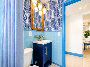 A bathroom with a toilet, sink, and mirror. - Coastal Haven | Pet-Friendly | Near the Beach | Treasure Island (Treasure Island)