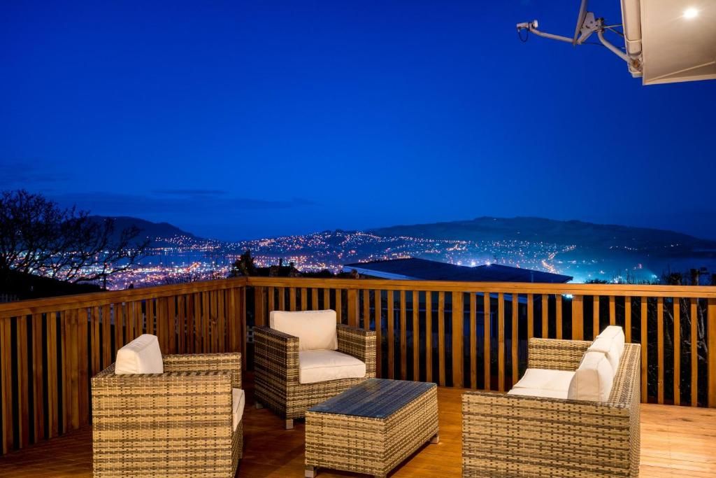 A balcony with wicker furniture and a view of a cityscape at night.
