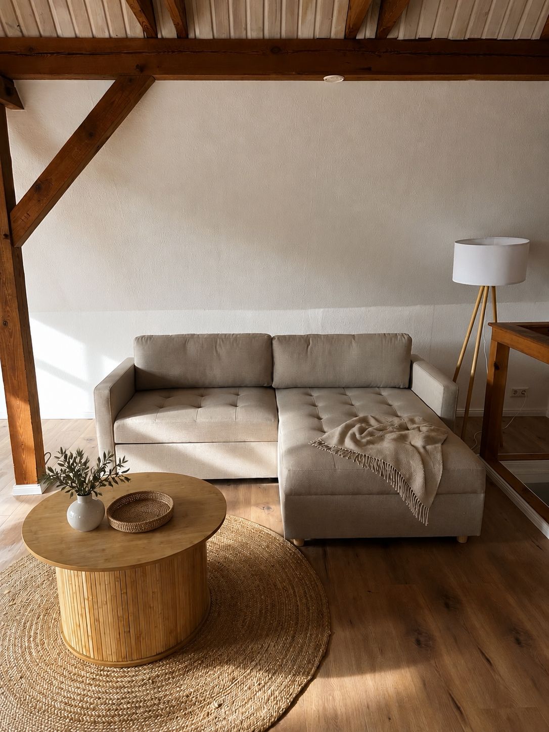 Ein modernes Wohnzimmer mit einer Eckcouch, einem runden Holztisch und einer Stehlampe.
