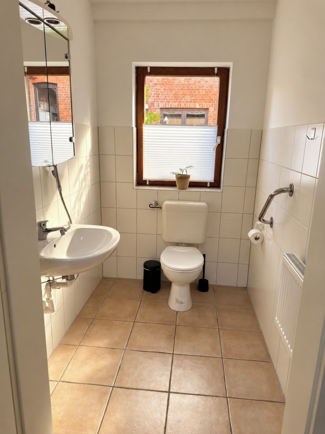 Ein kleines Badezimmer mit Toilette, Waschbecken und Fenster.