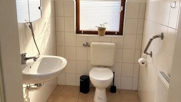 Ein kleines Badezimmer mit Toilette, Waschbecken und Fenster.