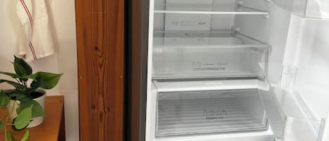 Una cocina con un refrigerador blanco, armarios de madera y una planta en maceta.