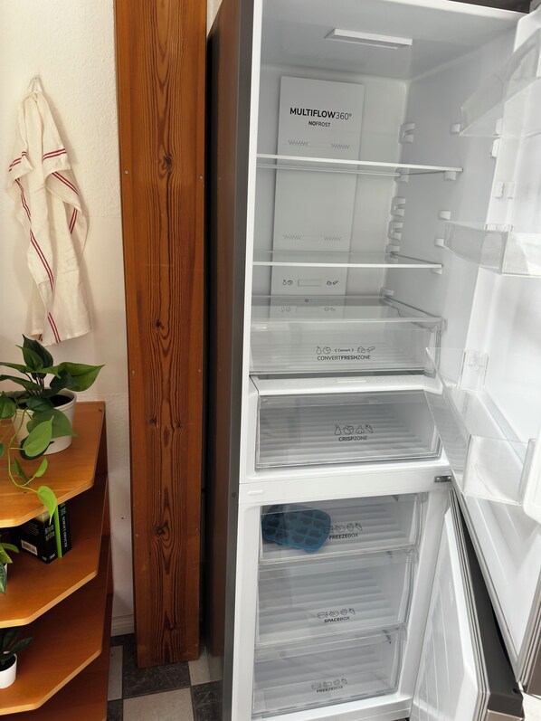 A kitchen with a white refrigerator, wooden cabinets, and a potted plant.