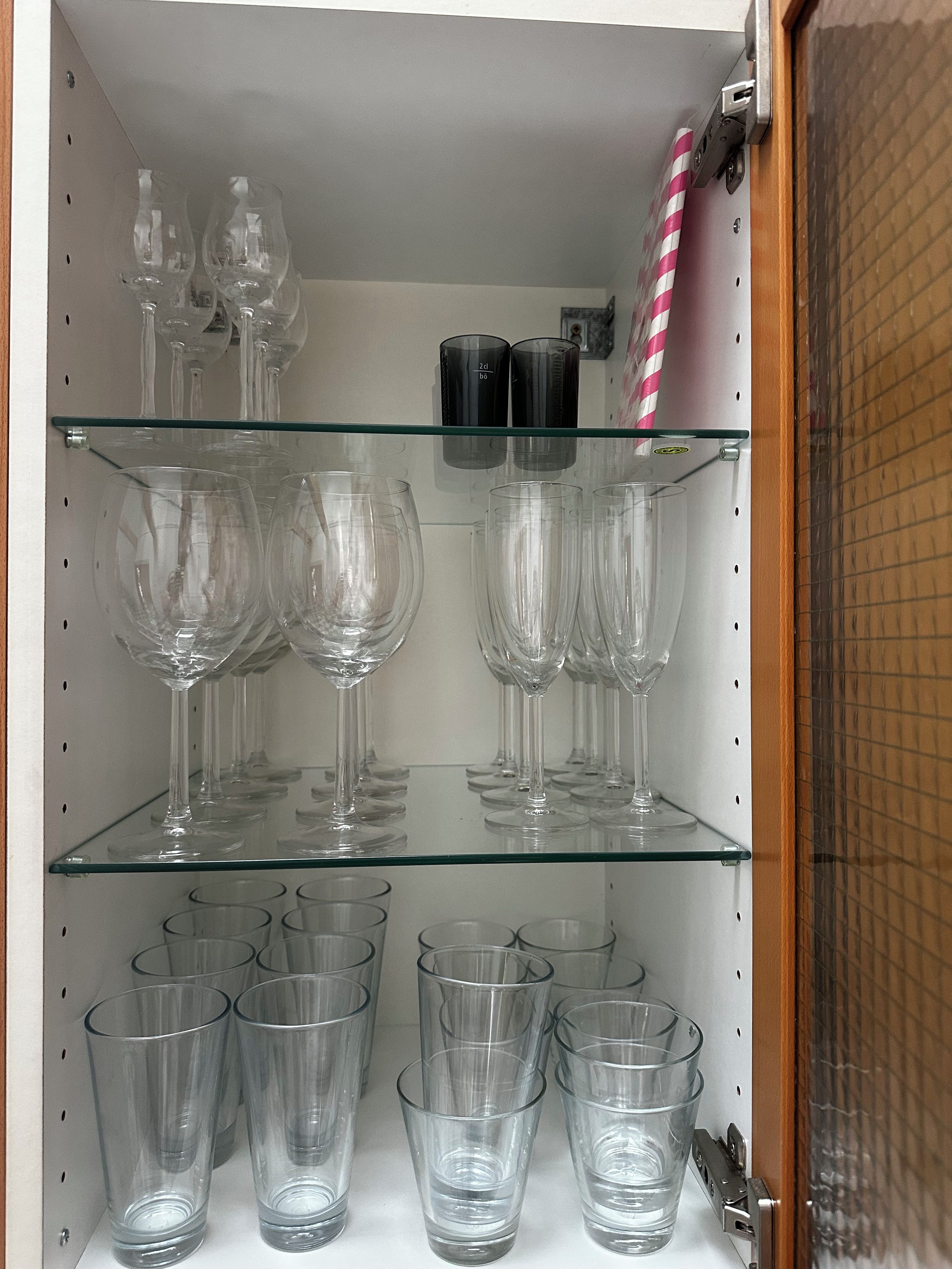Uno scaffale con diversi bicchieri, tra cui calici da vino e bicchieri tumbler.