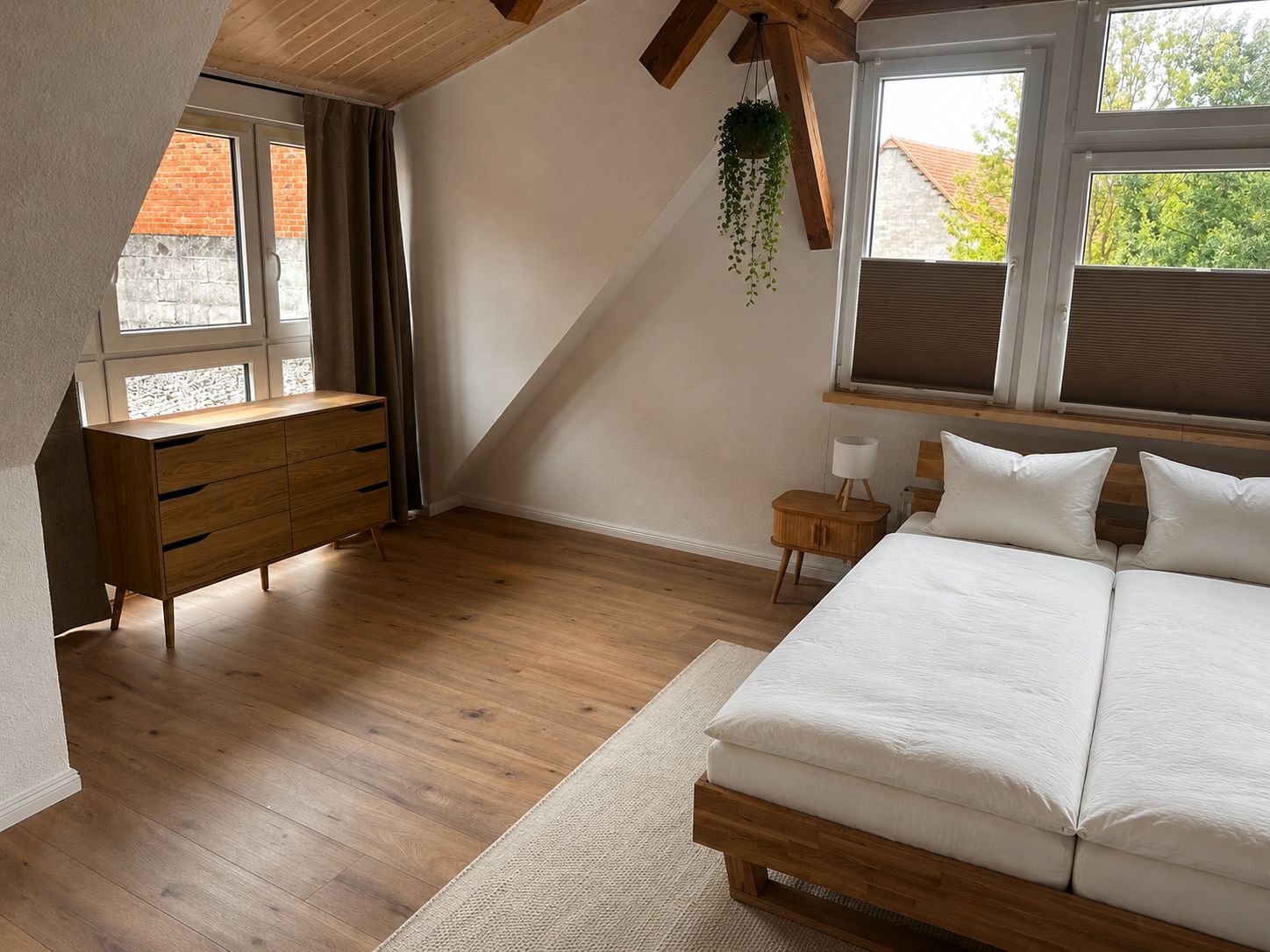 Ein Schlafzimmer mit einem hölzernen Bett, einem Schminktisch, einem Nachttisch und einer hängenden Pflanze.