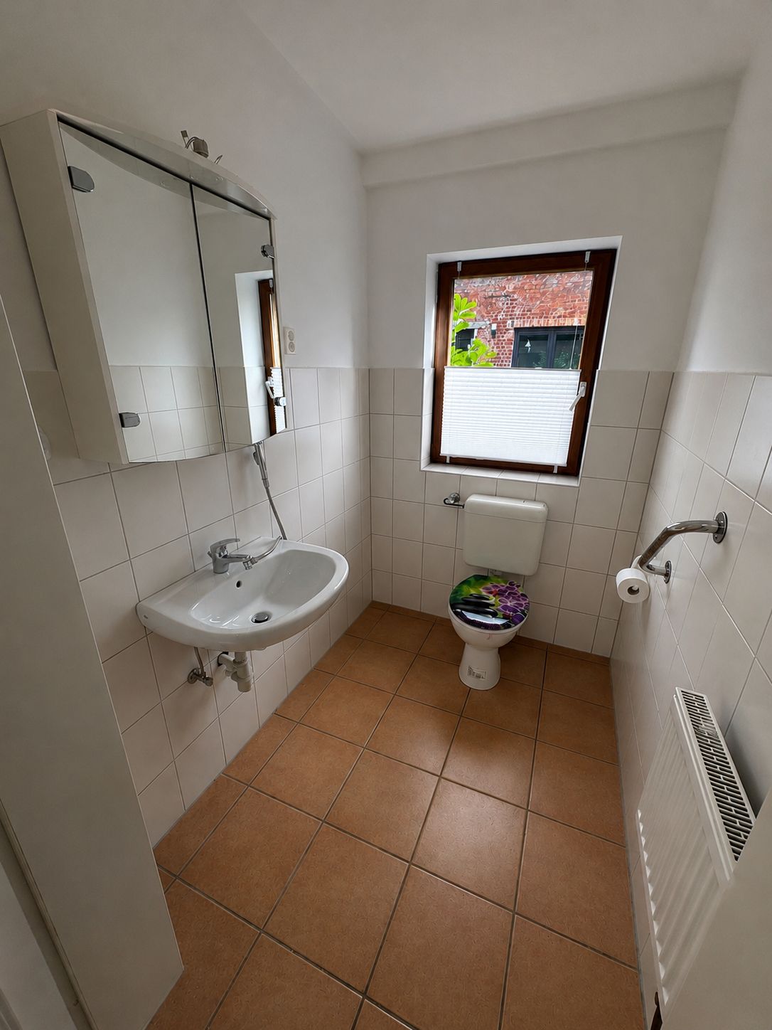 Ein kleines Badezimmer mit Waschbecken, Toilette und Fenster.