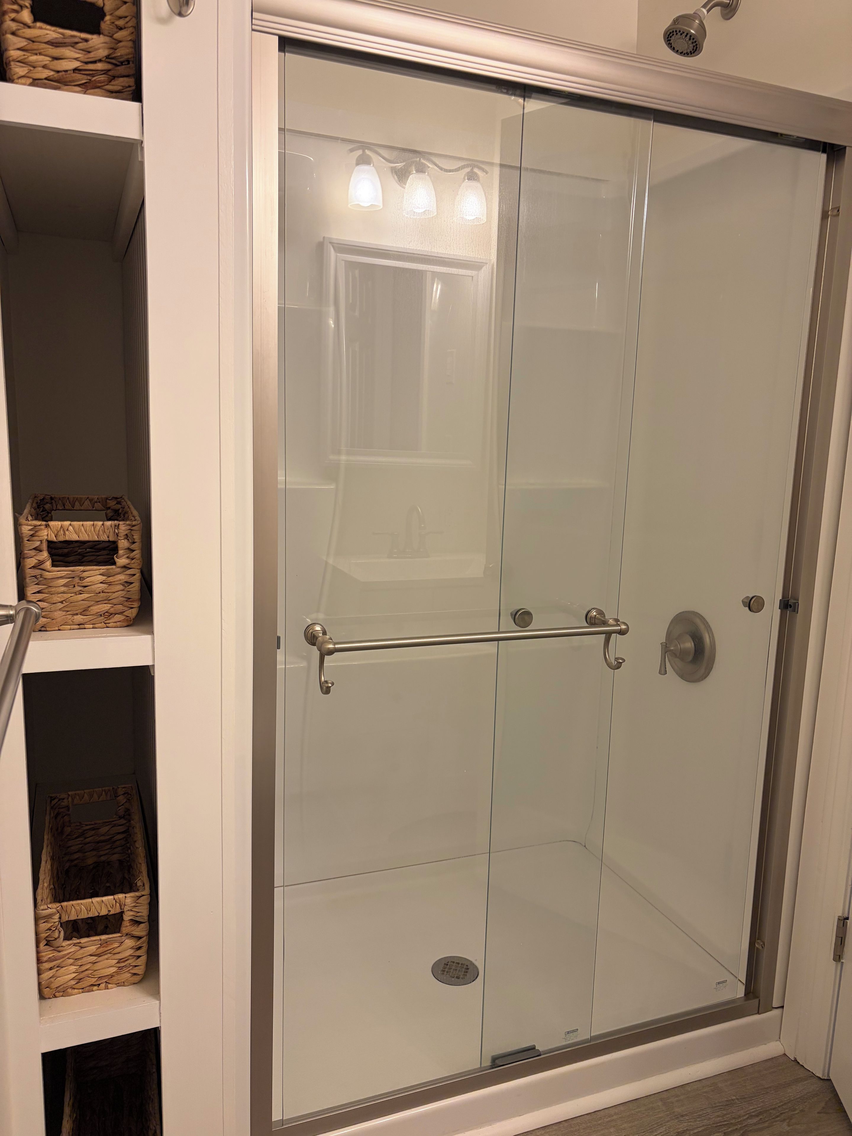A glass-enclosed shower with a metal handle and a towel rack.